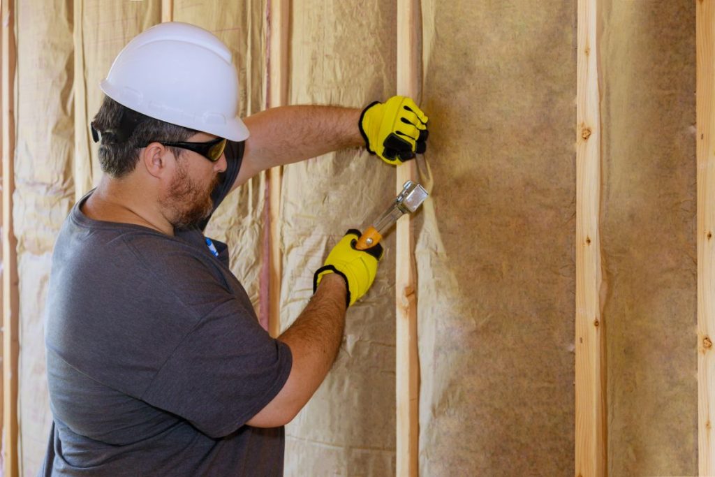 Man installing thermal insulation layer under the wall
