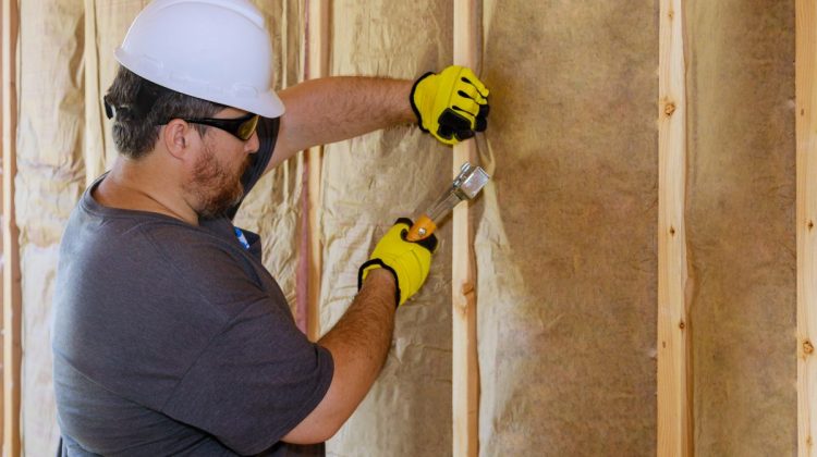 Man installing thermal insulation layer under the wall