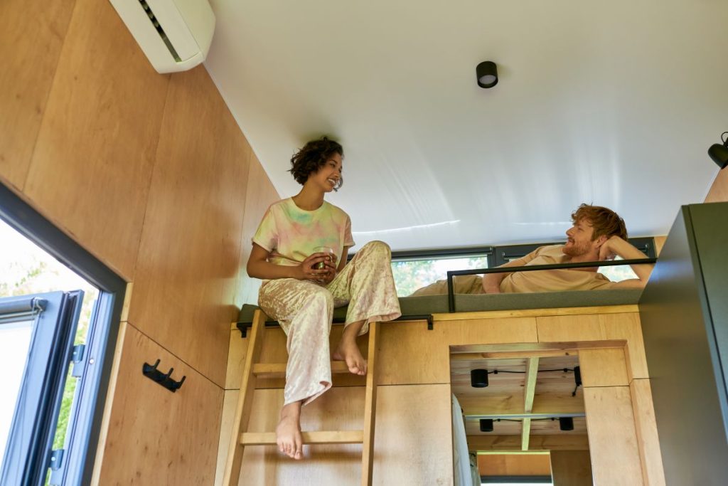 couple having morning coffee in tiny home loft bedroom